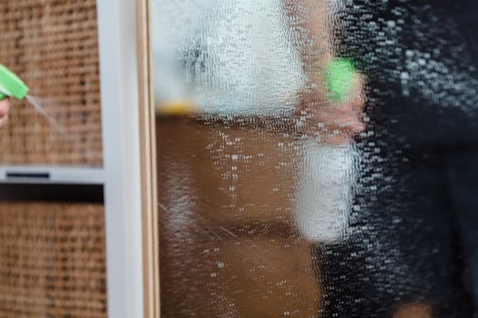 pexels-photo-9462099-9462099 Detailed view of a mirror being cleaned using a water sprayer, indoors.